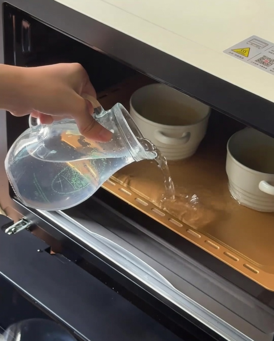 オーブン皿に入れたココットに湯を注いでいる様子