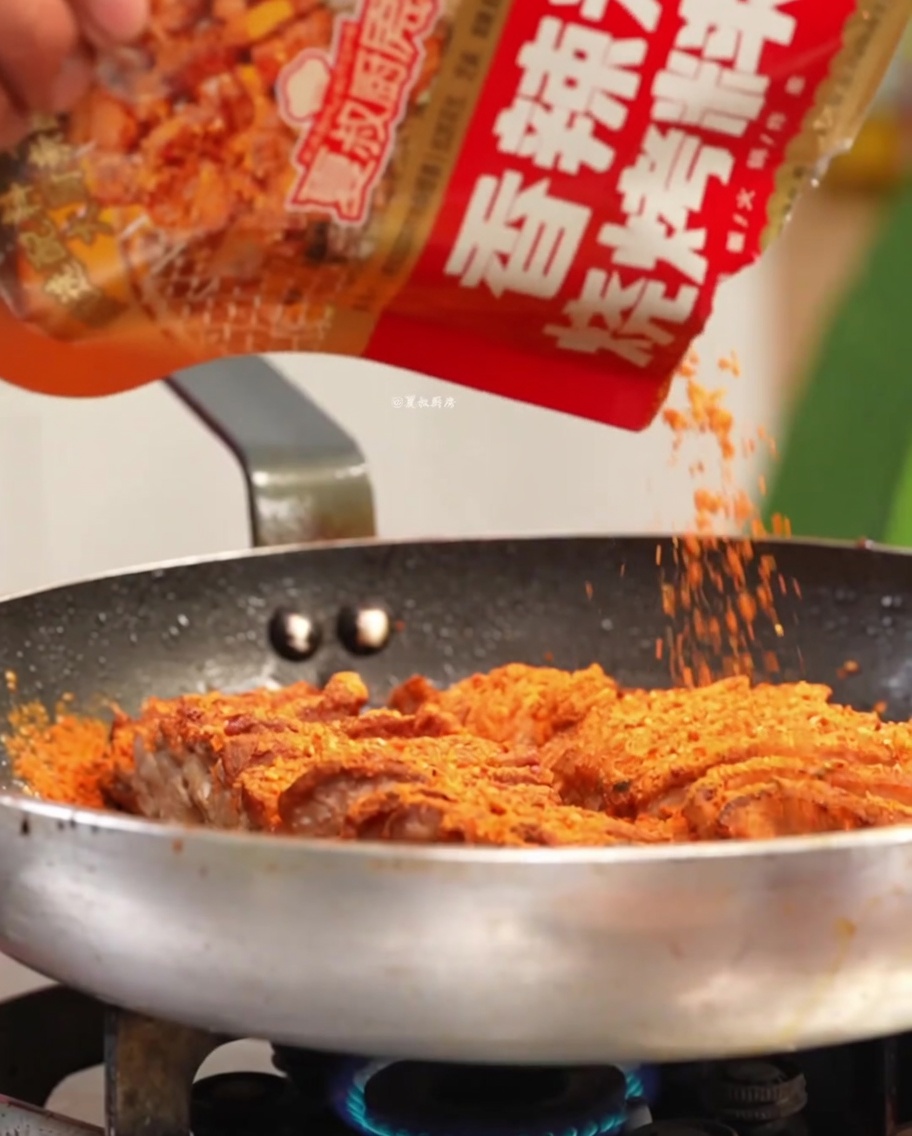 熱したフライパンでスパイスや香味野菜と一緒に味付けされている豚肉。