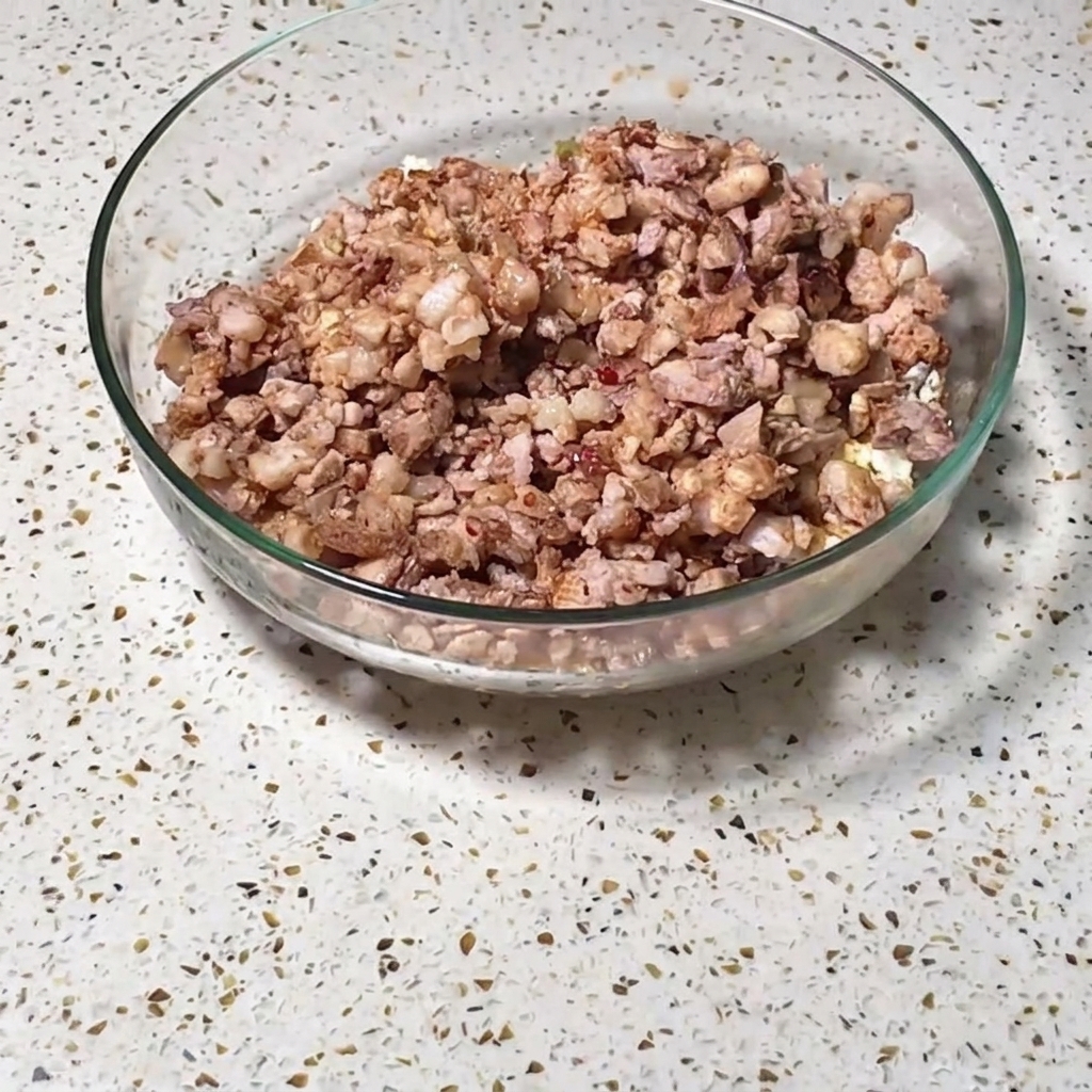 細かく刻んだ肉、卵、炒めた野菜やスパイスの混合物が入った、大きめの透明なガラスボウル。