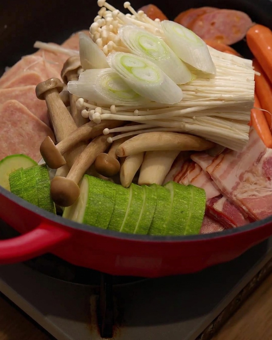 鍋の中の食材の上に、新しくスライスした長ネギの小口切りが置かれている様子。
