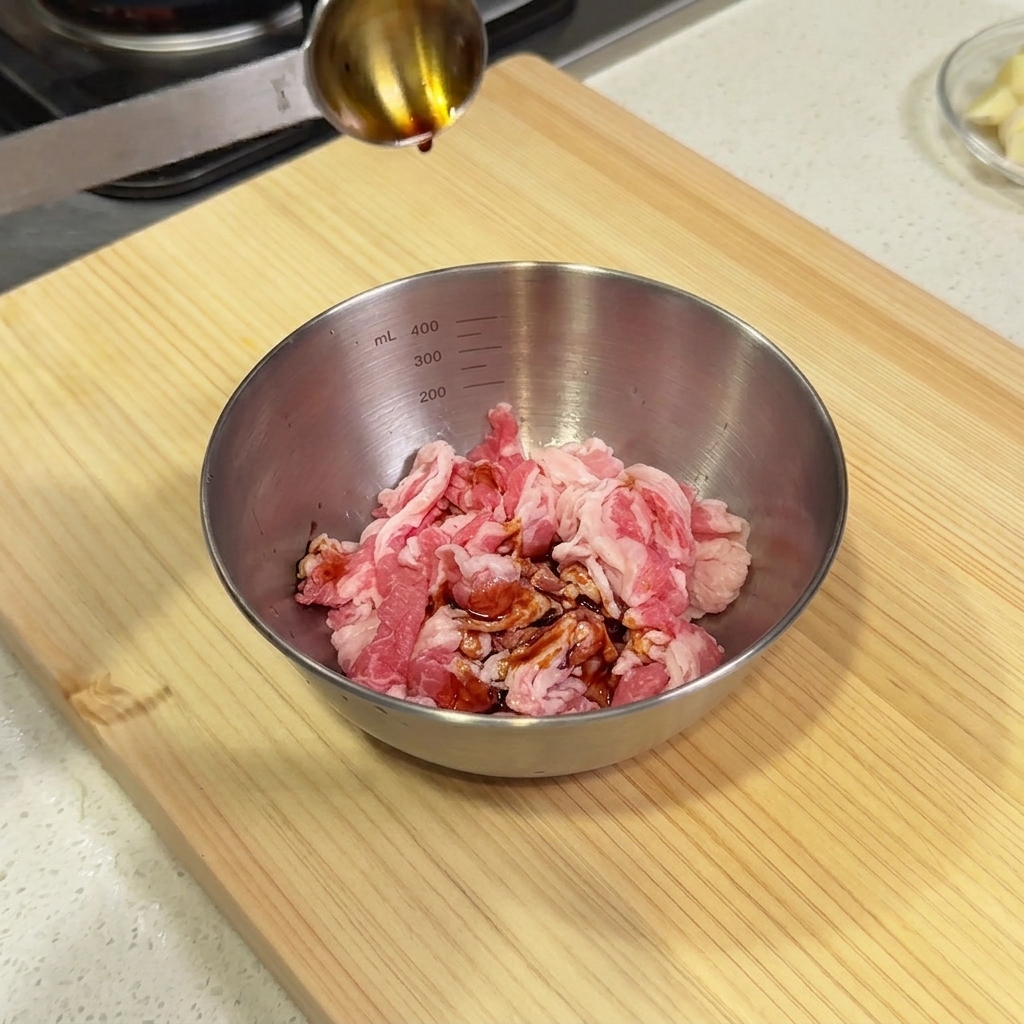 生の牛肉が入ったボウルに薄口醤油などの調味料を注いでいる様子