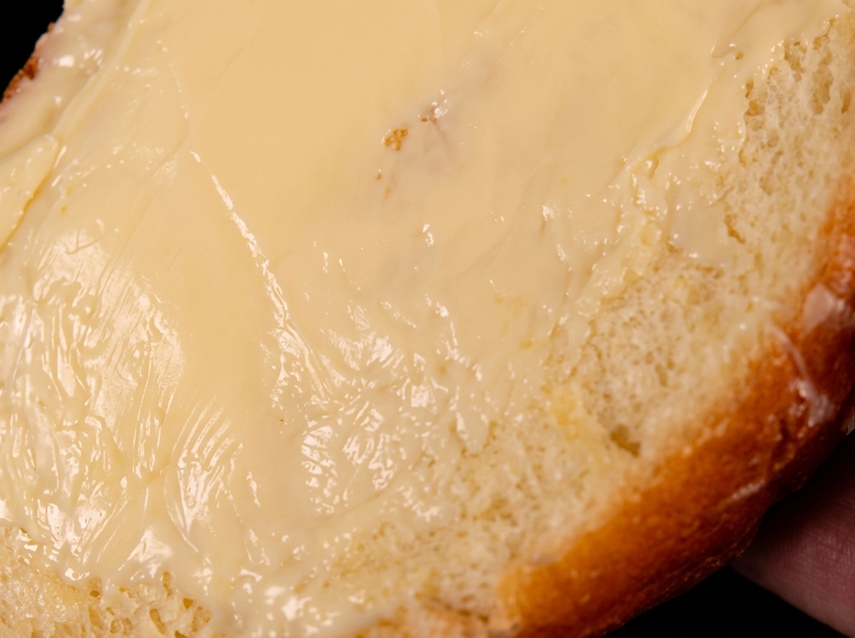 片面にバターを塗った食パンが、バターの面を下にして熱いフライパンに置かれている様子。