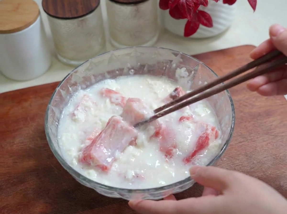 塩と小麦粉が入ったスペアリブのボウルに水を注ぎ、箸で混ぜ合わせている様子。