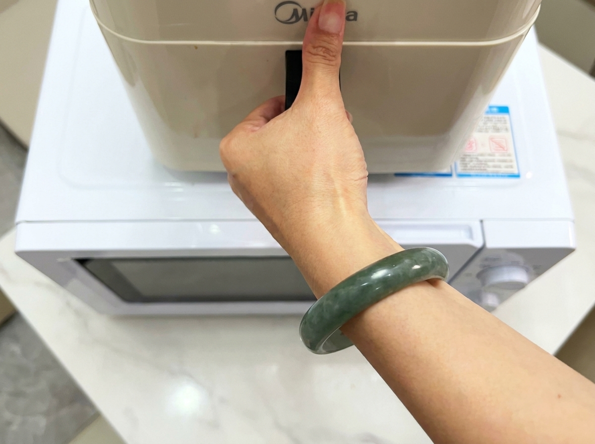 白い表面に置かれたモダンなキッチンの調理家電のハンドルを手で持っている様子。