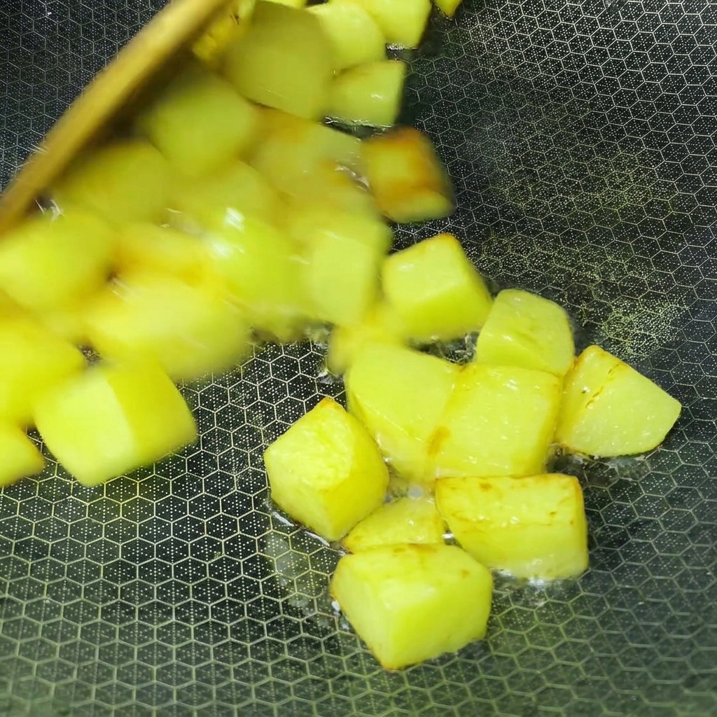中華鍋で黄金色になるまで揚げ焼きにされている角切りのじゃがいも。