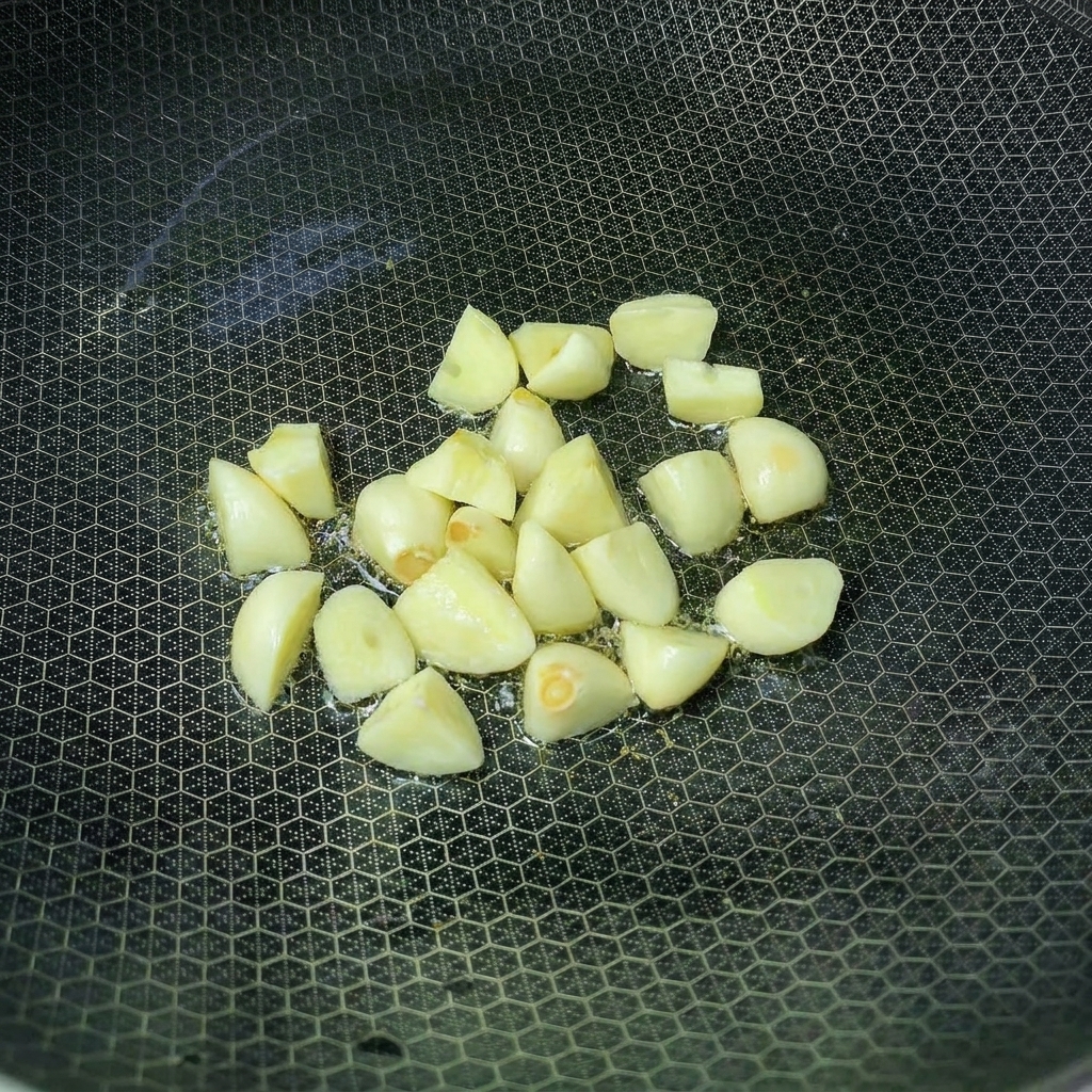 熱した油を入れた中華鍋でにんにくを炒めている様子。