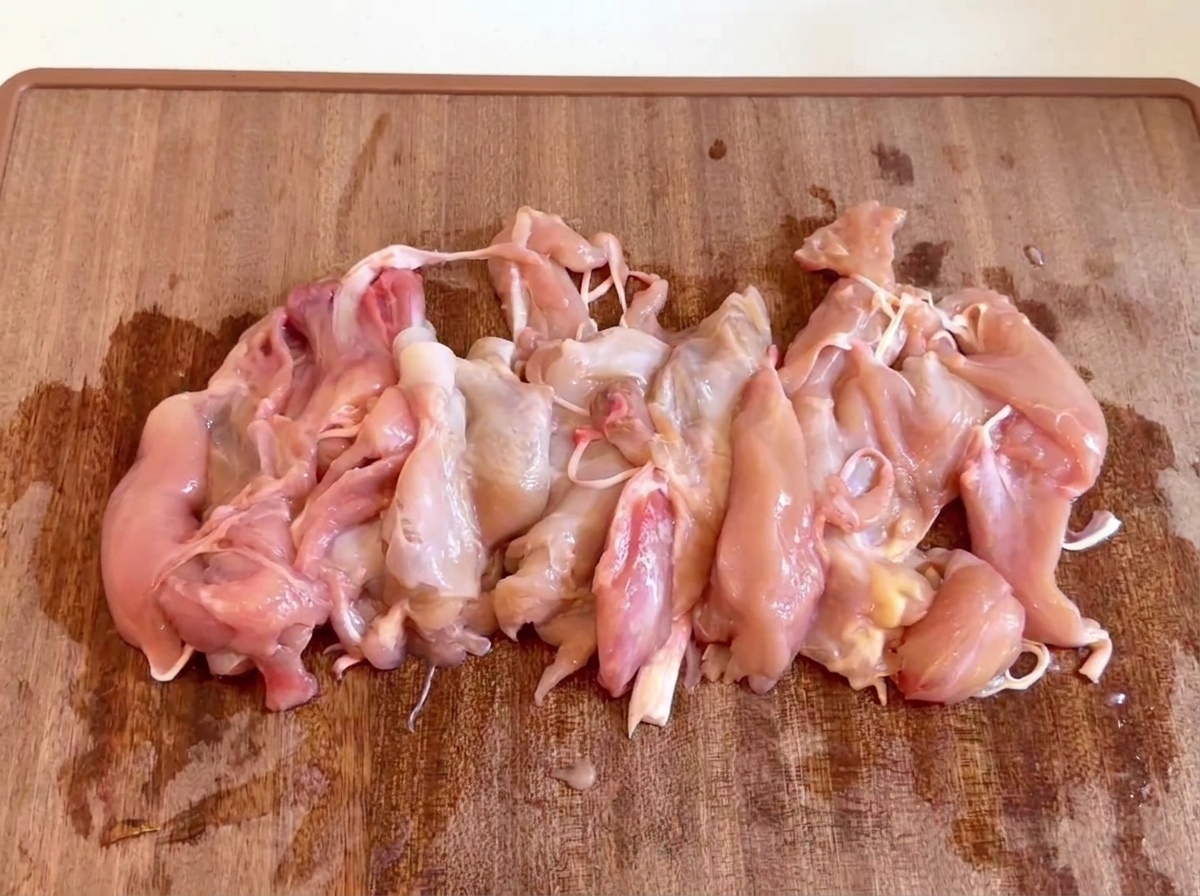 木製まな板の上に集められた、生の骨抜き鶏肉の切り身。
