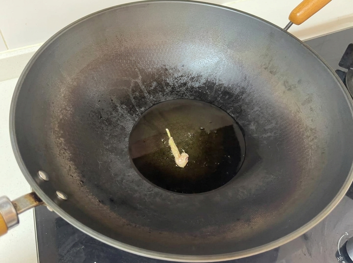熱い油が入った大きめの中華鍋の中央で、粉をまぶした鶏肉が一つ揚げられている様子。