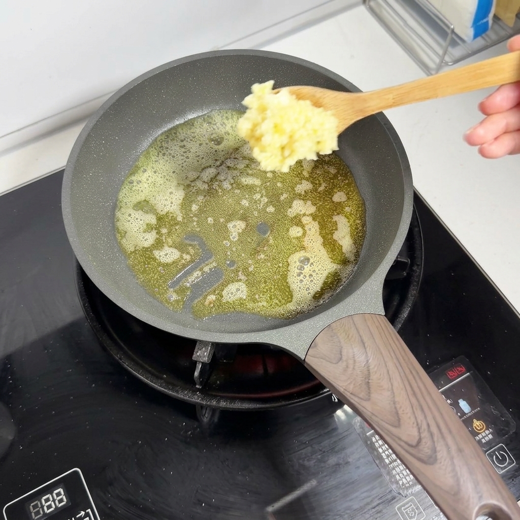 泡立つ溶かしバターの中に、木べらを使ってみじん切りニンニクを加えているところ。