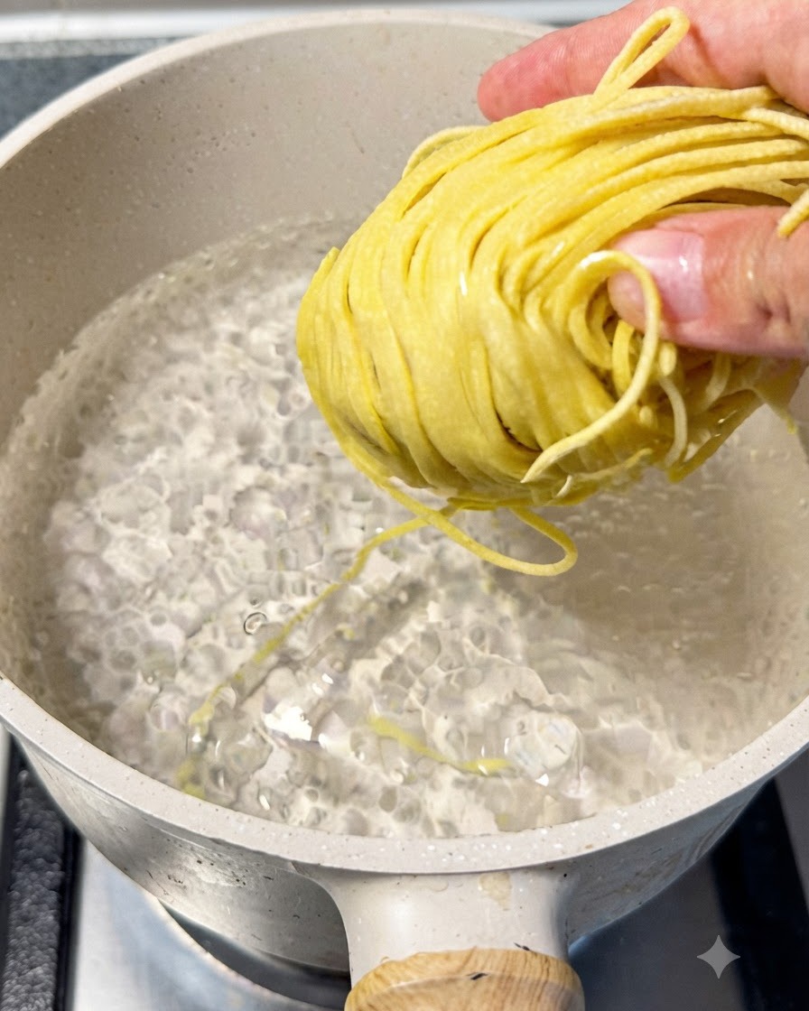 鍋で茹でられているラーメンの麺を、菜箸で持ち上げて茹で加減を確認している様子。