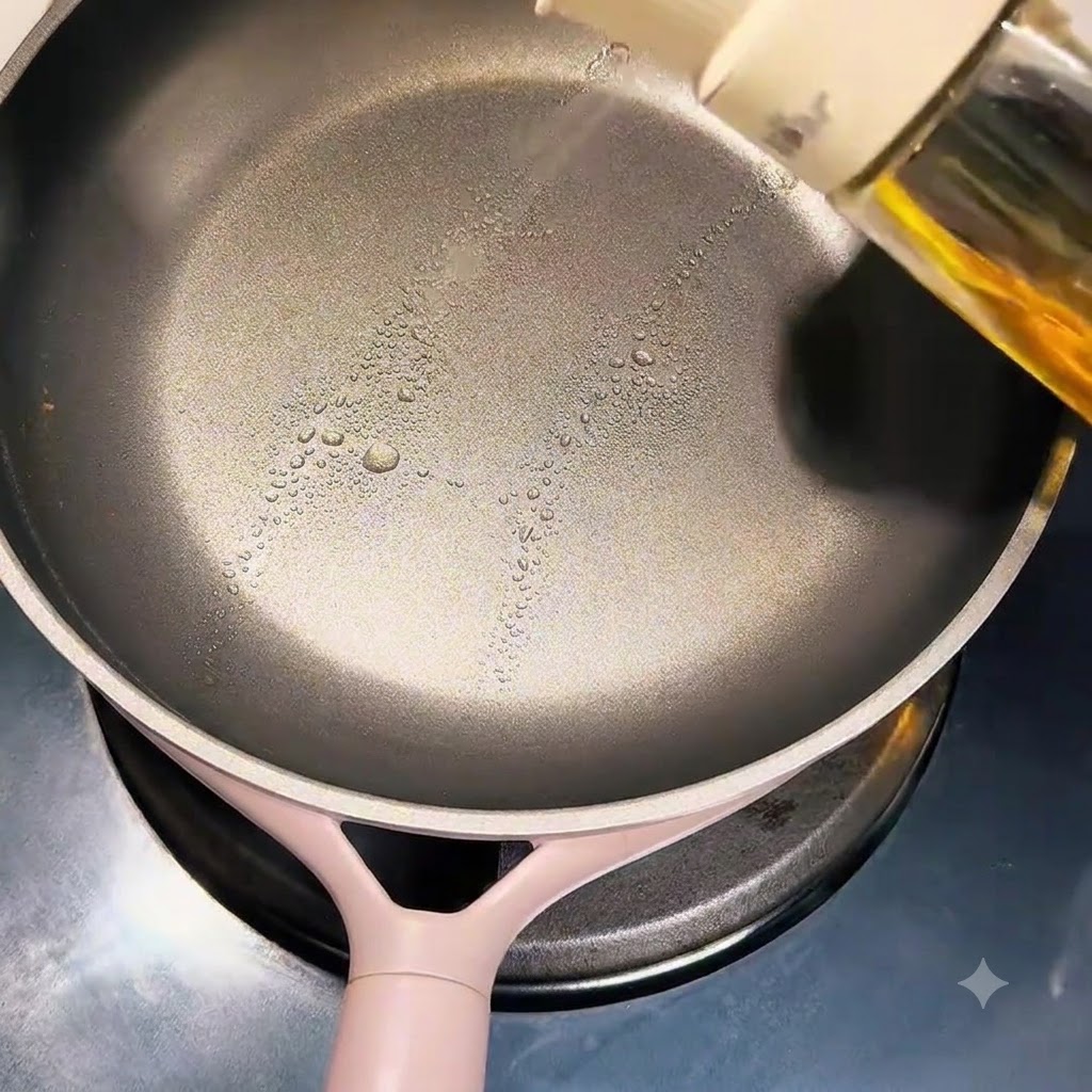 きれいなフッ素樹脂加工のフライパンにスプレー式の調理油を吹きかけている様子