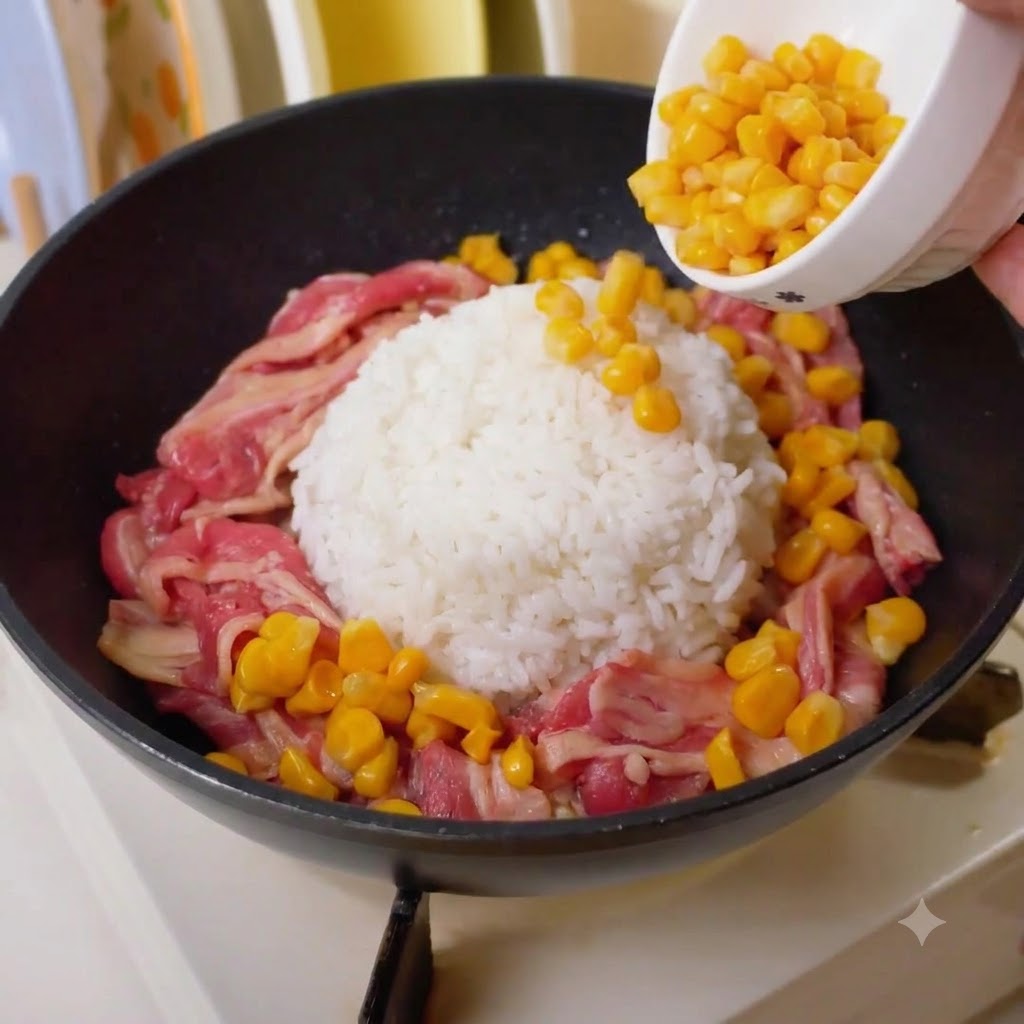 牛肉とご飯の隙間に、黄色いコーンを小さなボウルから注ぎ入れている様子。