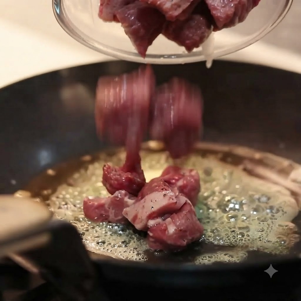 溶けたバターが泡立つ熱々のフライパンに、下味をつけた生肉をボウルから流し込んでいる様子。