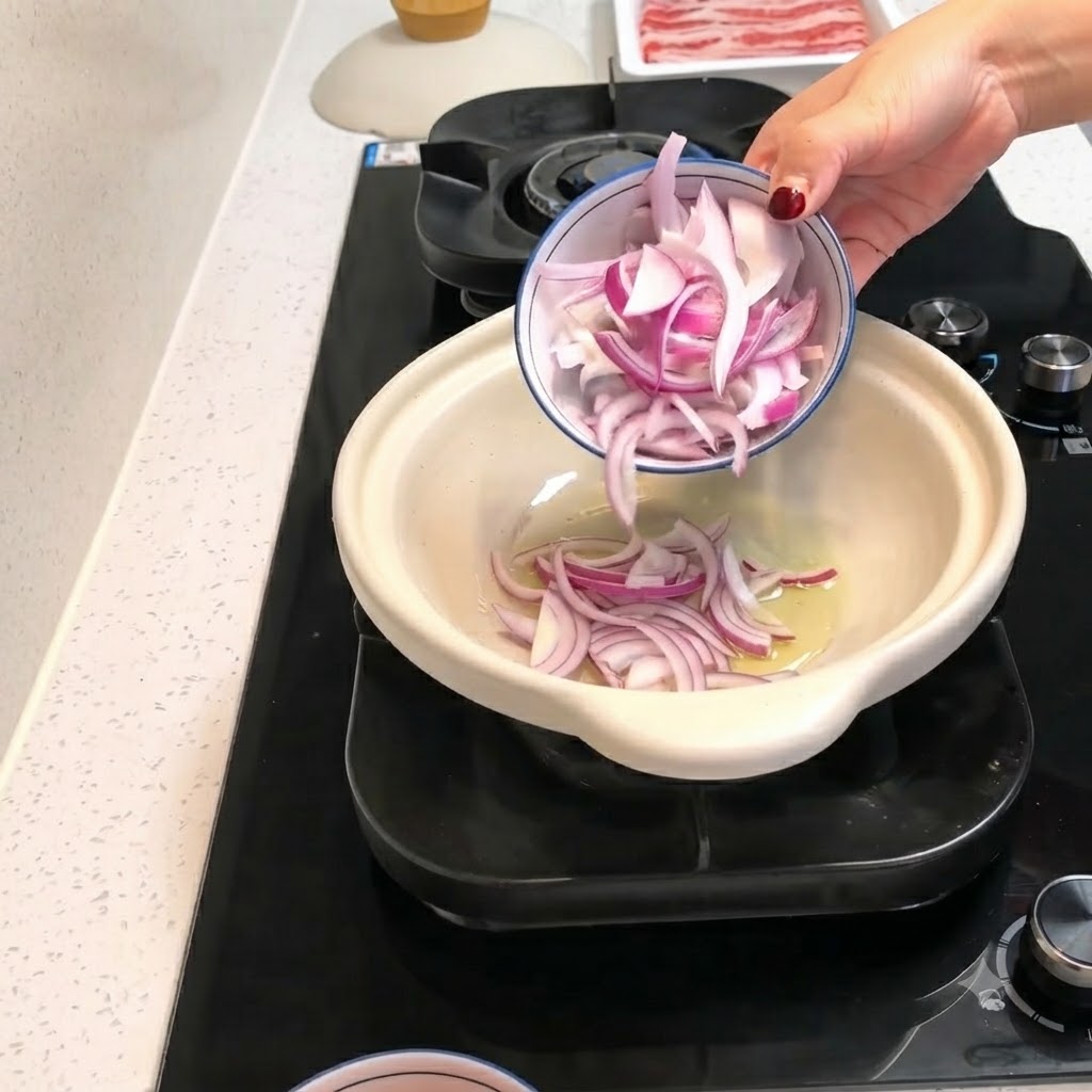 赤玉ねぎのスライスと皮をむいたトマトのピースが、油を引いた熱々の土鍋的小皿から投入される様子。