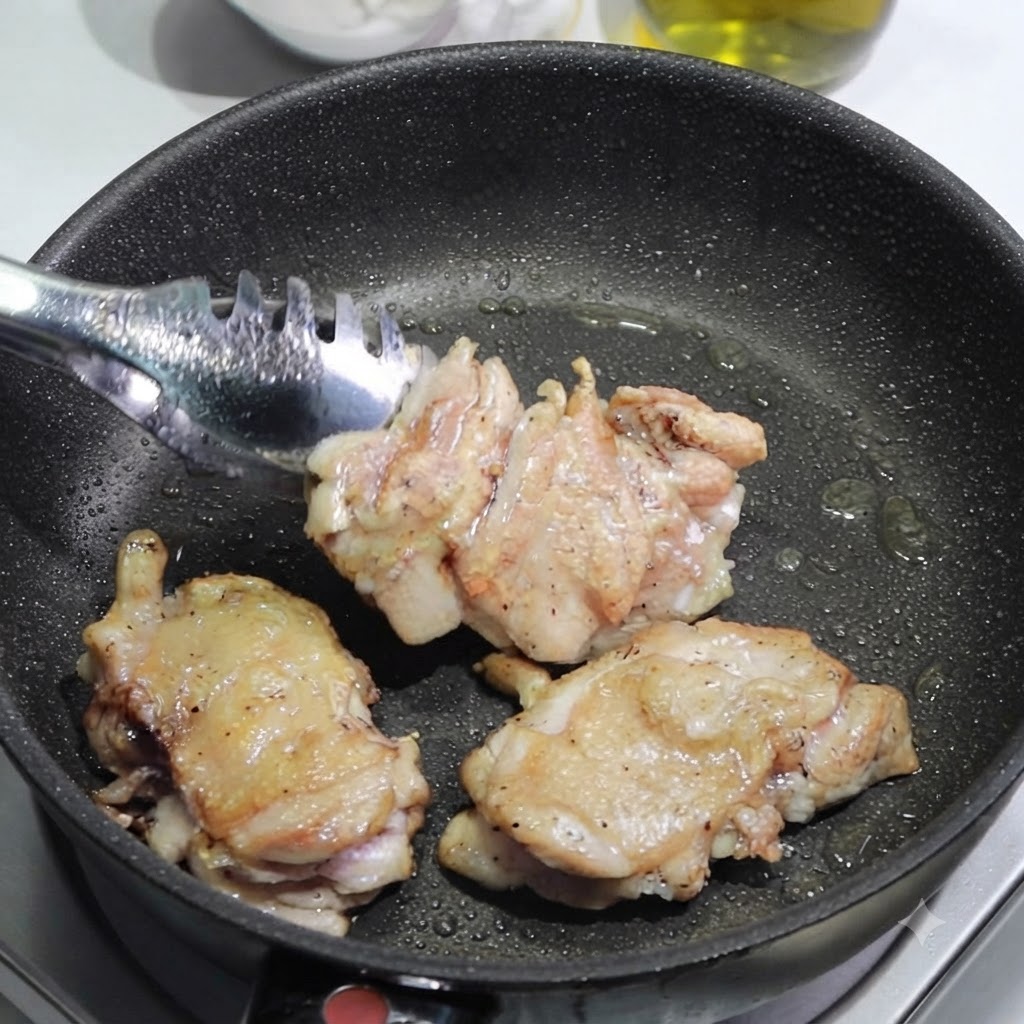 トングを使って、焼き色がついた鶏もも肉をフライパンからまな板に移してスライスしているところ。