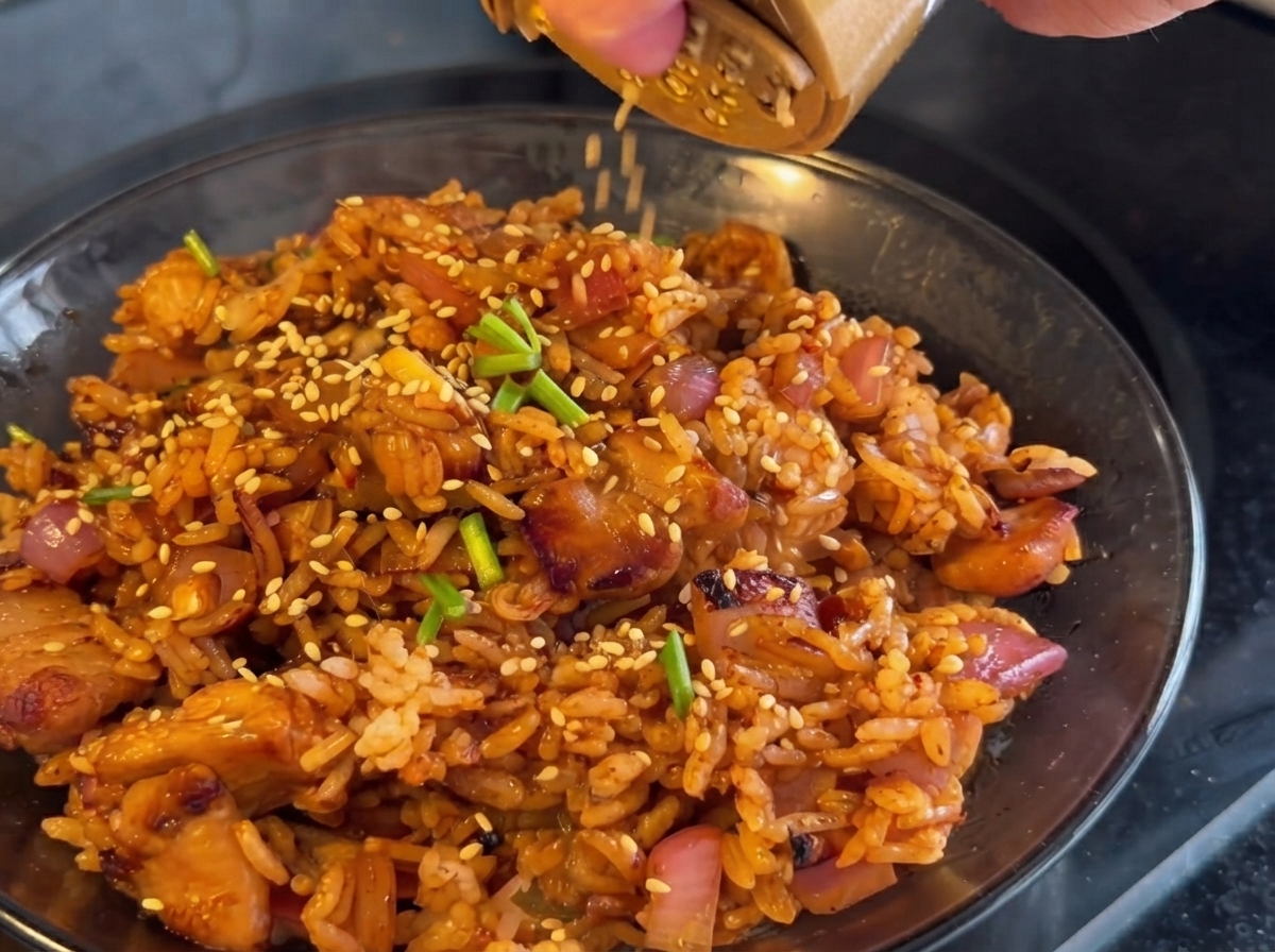フライパンにキムチを加え、鶏肉や玉ねぎと一緒に炒めている様子。