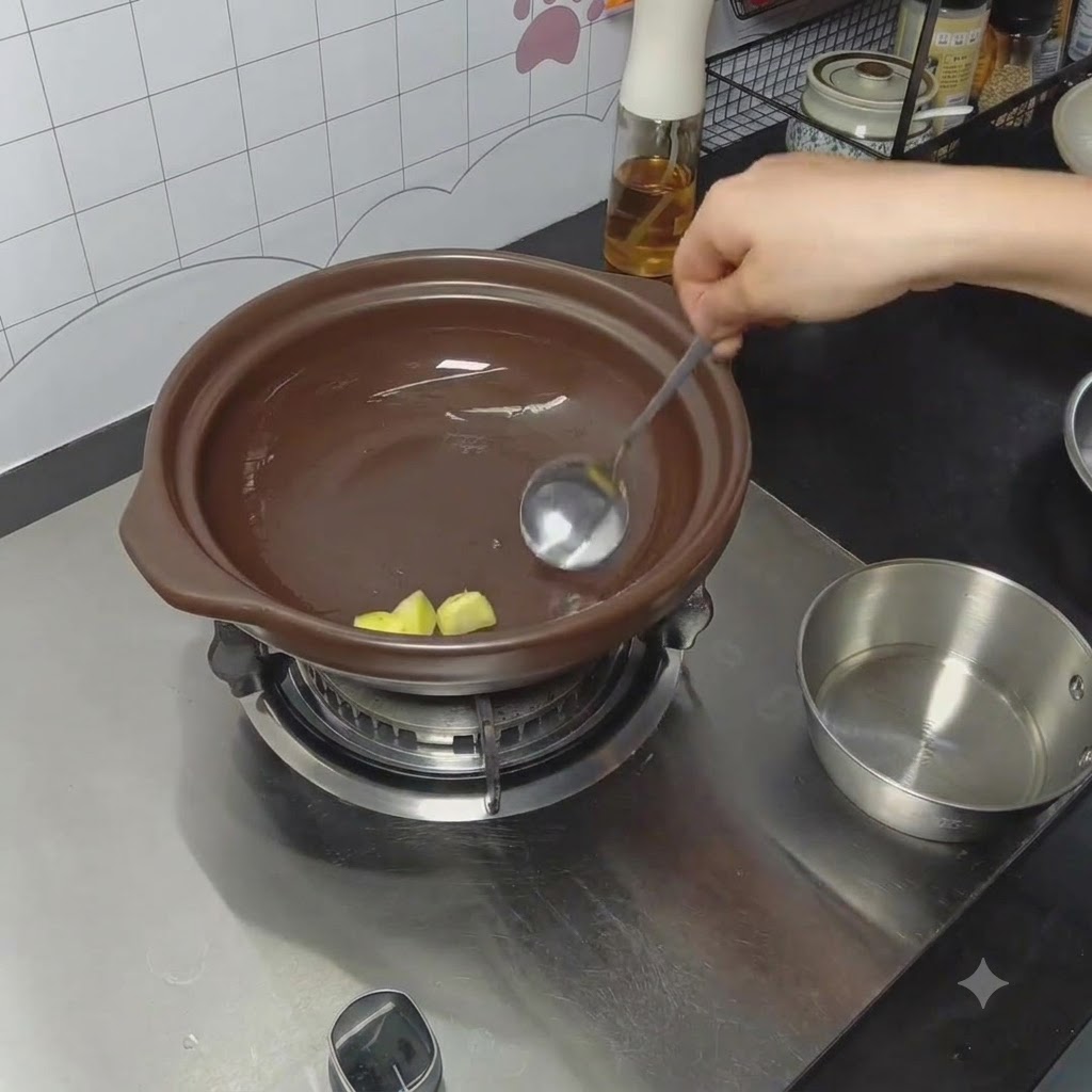 スプーンを使って土鍋の底に油と生姜をすり込んでいる様子。