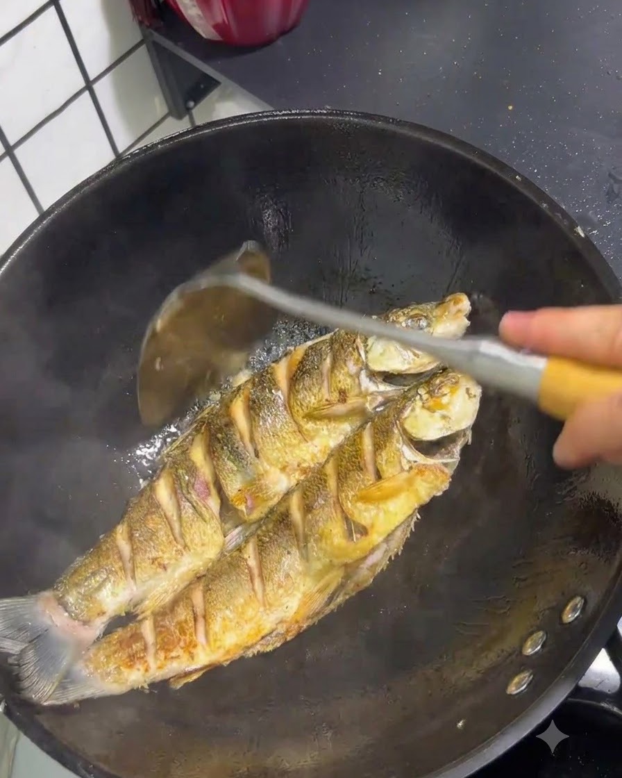中華鍋の中で、スパチュラで皮がきつね色に焼けていくいとより鯛を調理している様子。