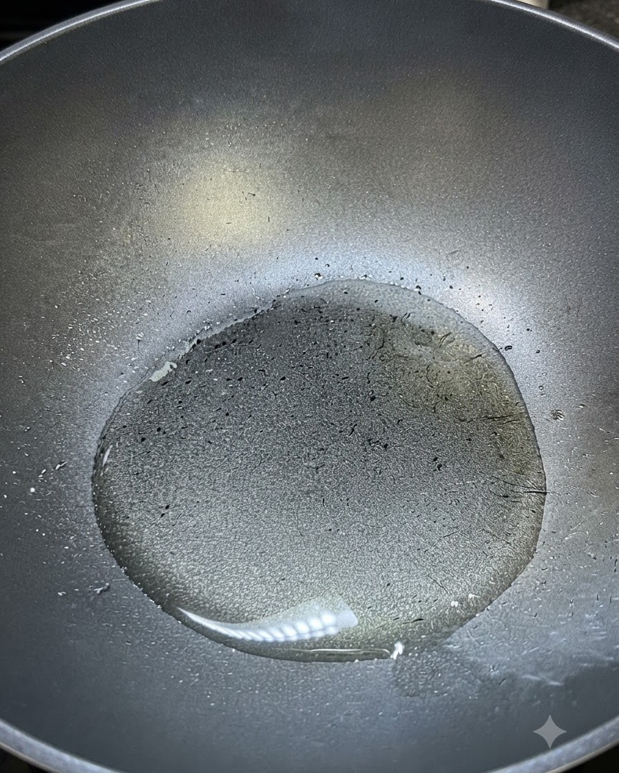 調理用の熱した油がゆらめき、味付けの準備ができている黒いフライパンの中。