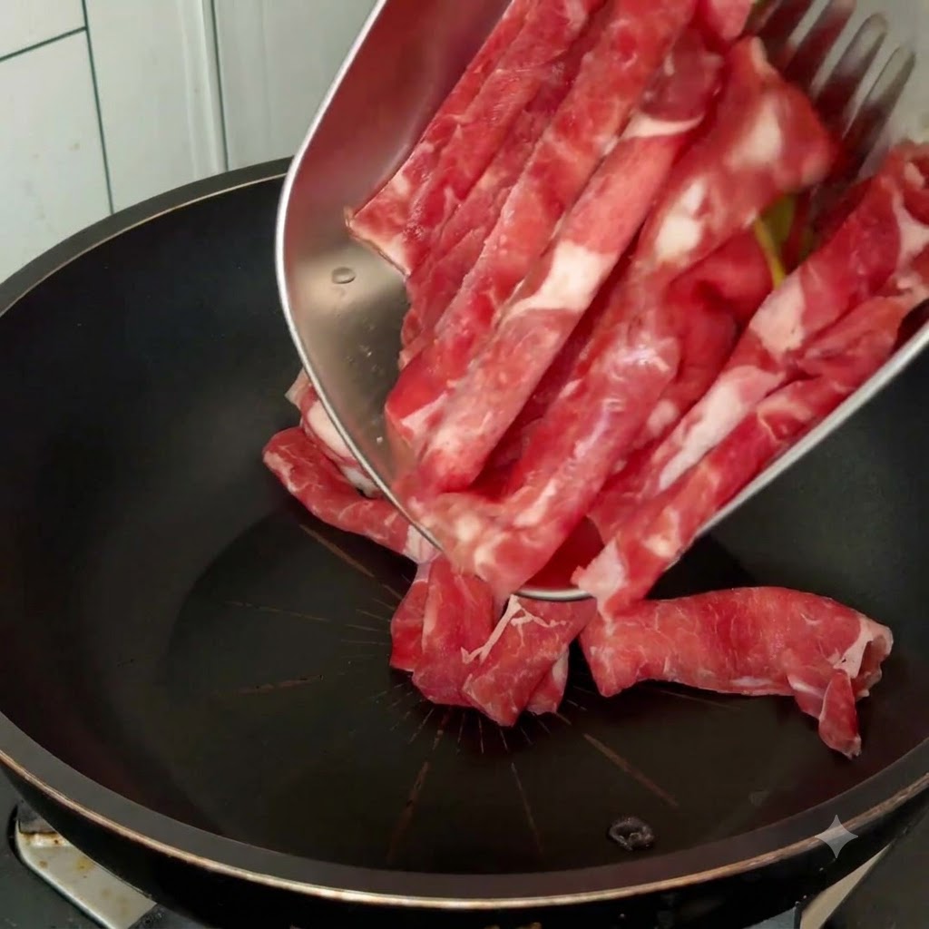 メタルプレートから黒いフライパンへと生の牛肉のスライスを移し入れて調理している様子