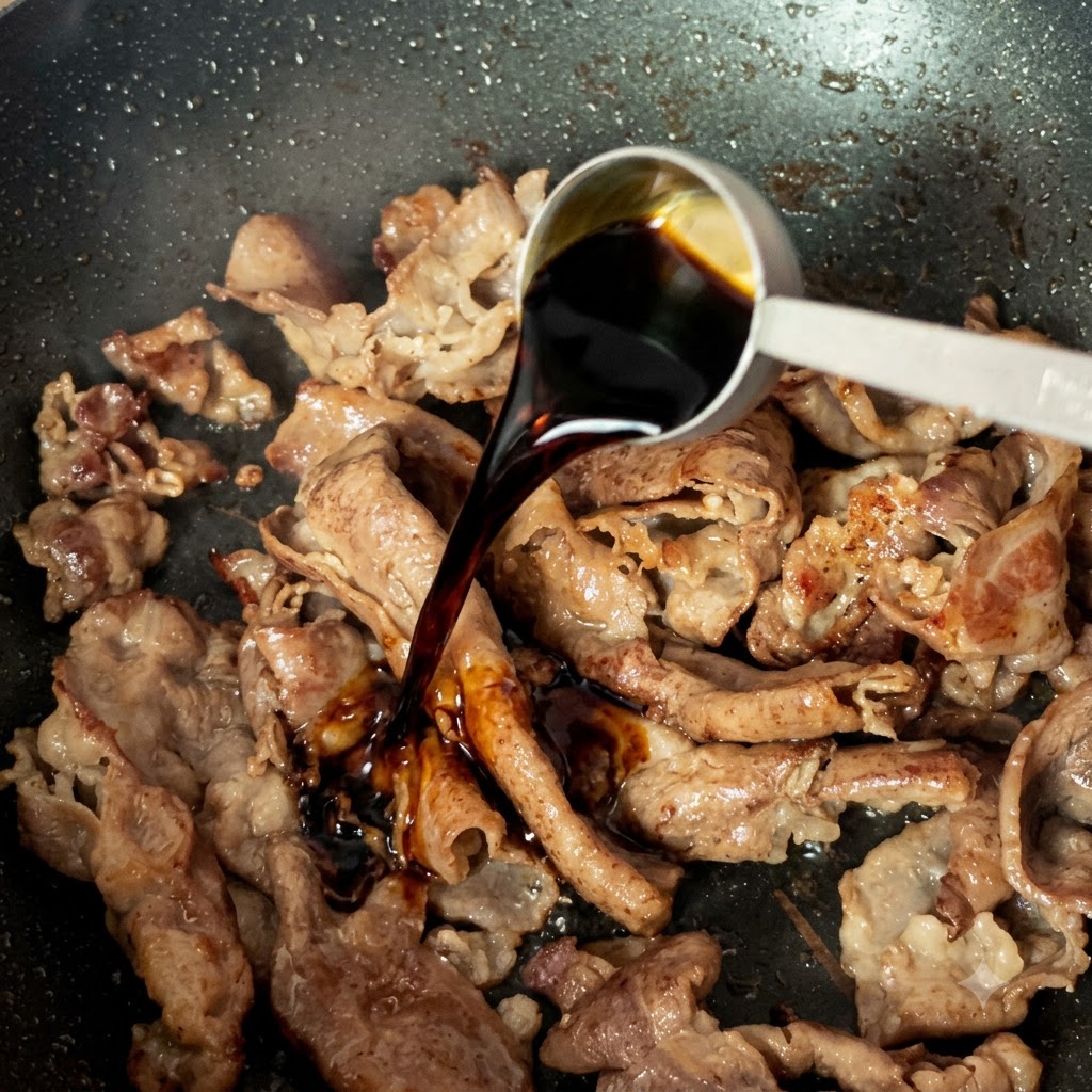 調理中の牛肉が入ったフライパンに、計量スプーンで薄口醤油を注いでいる様子
