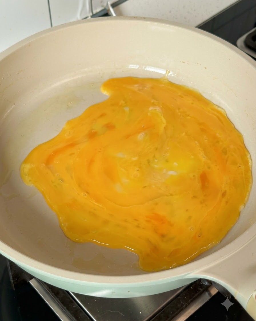 熱したフライパン全体に、溶き卵が広がって薄焼き卵を作っている様子