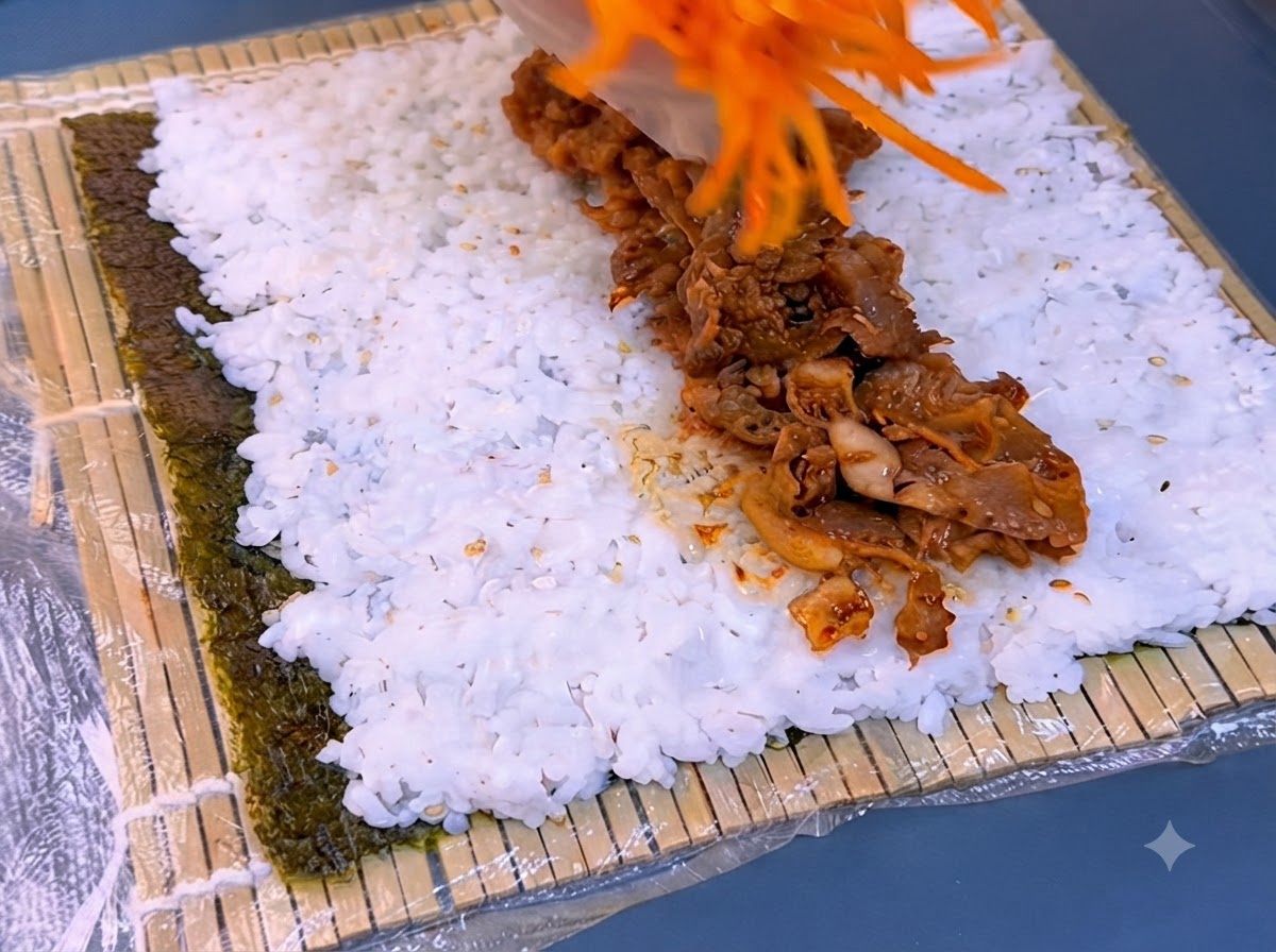ご飯の上に並べられた焼肉と千切り人参