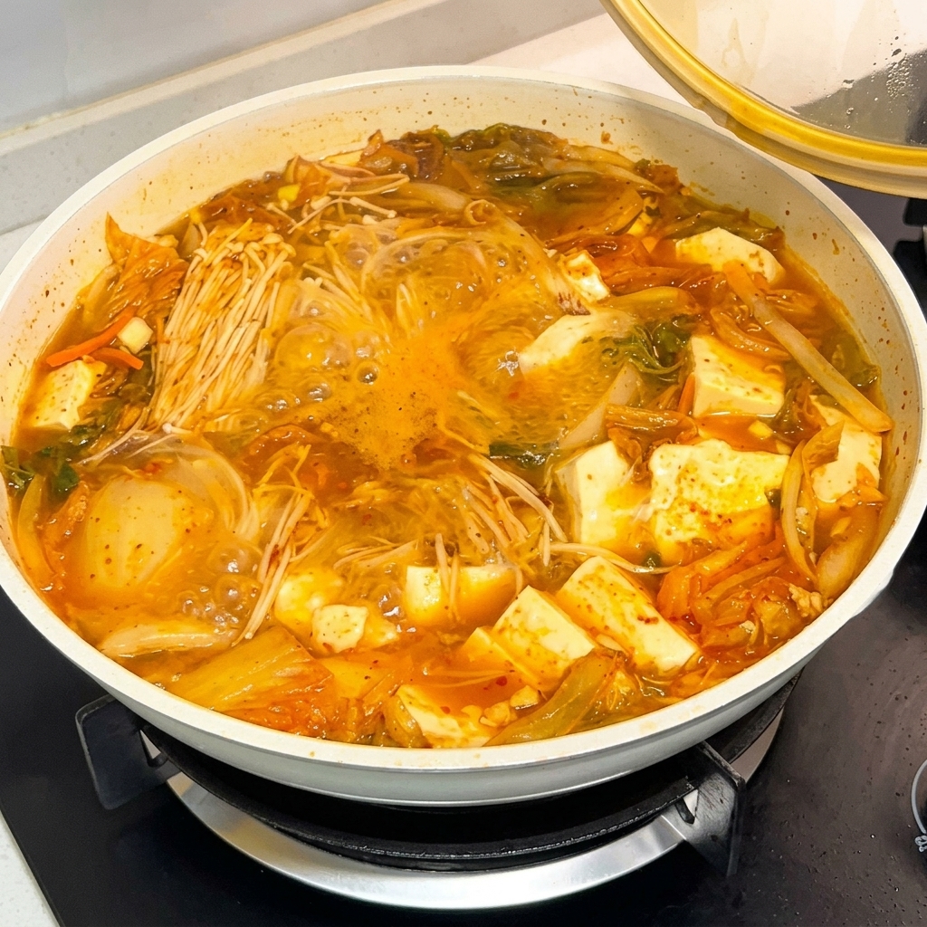 グツグツと煮えるスープの鍋に、韓国産唐辛子味噌ソースをスプーン1杯加えている様子。