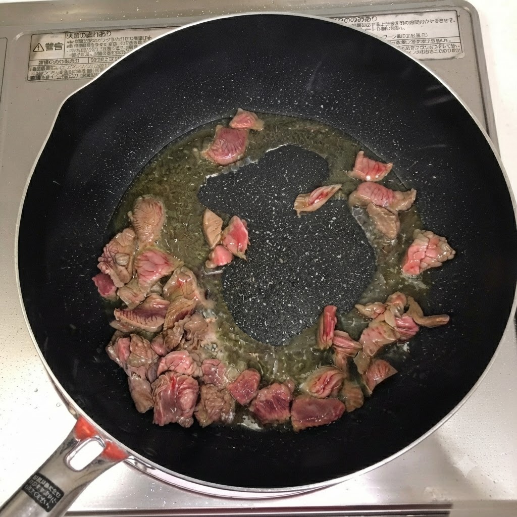 フライパンの中の牛肉に、料理酒、粉唐辛子、コチュジャンが加えられている様子