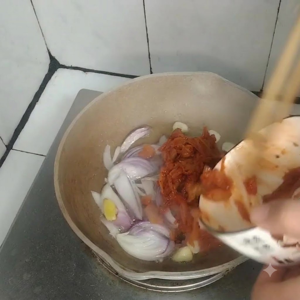 炒めた玉ねぎ、にんにく、生姜が入ったフライパンに、小さなボウルからキムチを投入している様子。