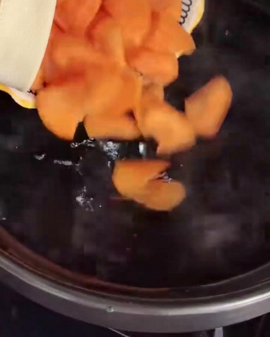沸騰した鍋のお湯にスライスしたにんじんを入れている様子。