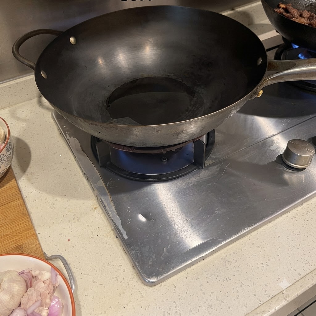 油をひいた熱々の中華鍋でジューシーに炒められている豚バラ肉と赤玉ねぎ。