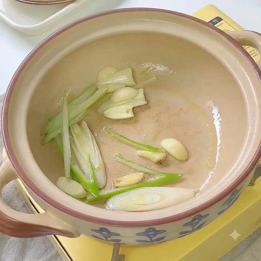 土鍋の中でキムチが長ねぎとにんにくと一緒に炒められている様子。