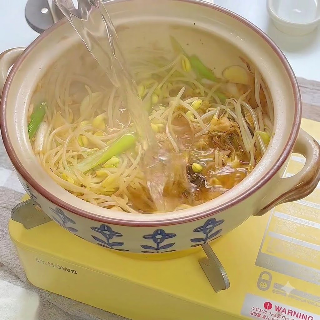 炒めた野菜のミックスが入った土鍋に水が注がれている様子。