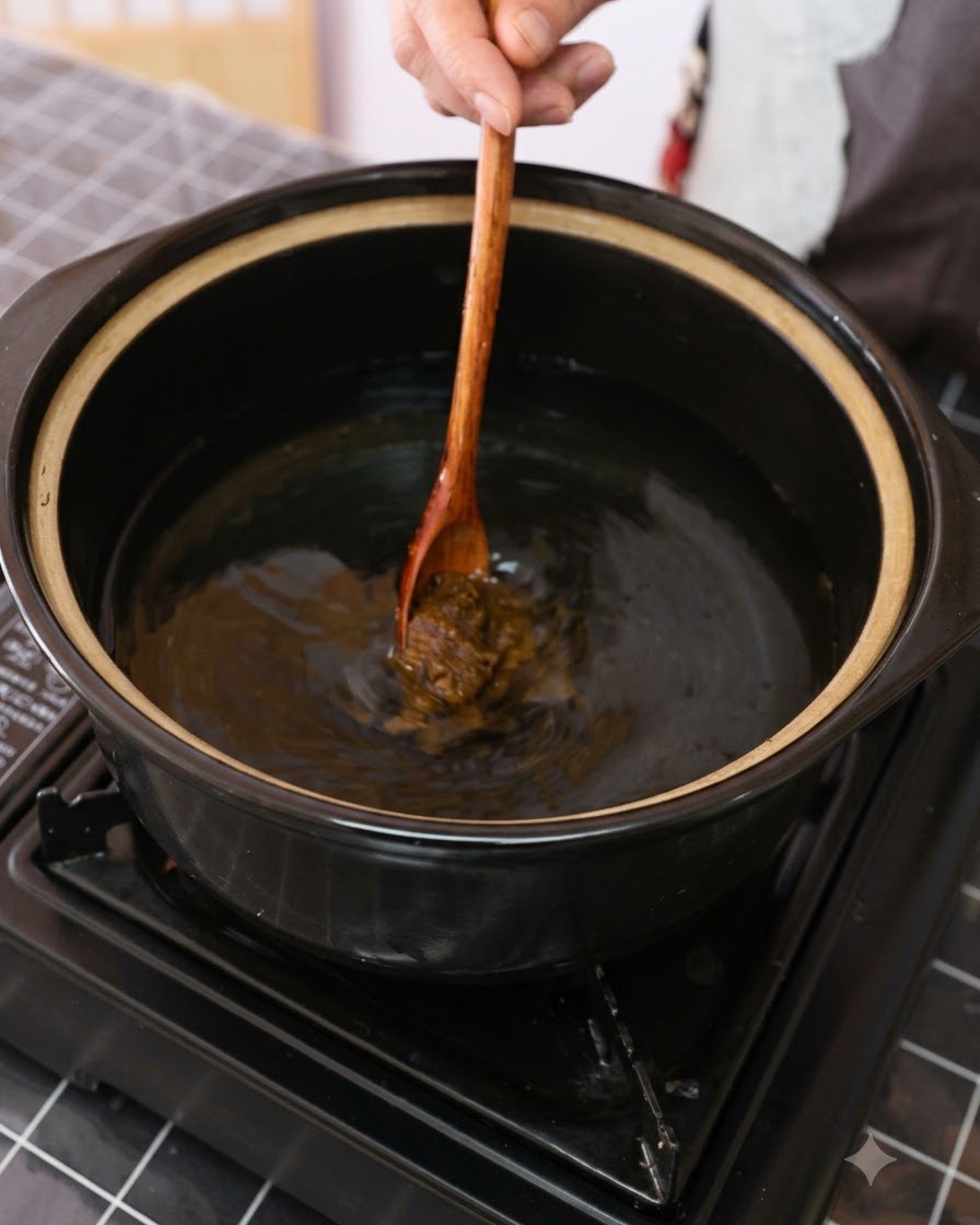 木製のスプーンを使って、水を入れた鍋に茶色いみそを溶かし入れている様子。