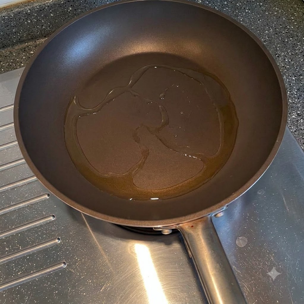 フライパンの油で玉ねぎのスライスが炒められている様子。