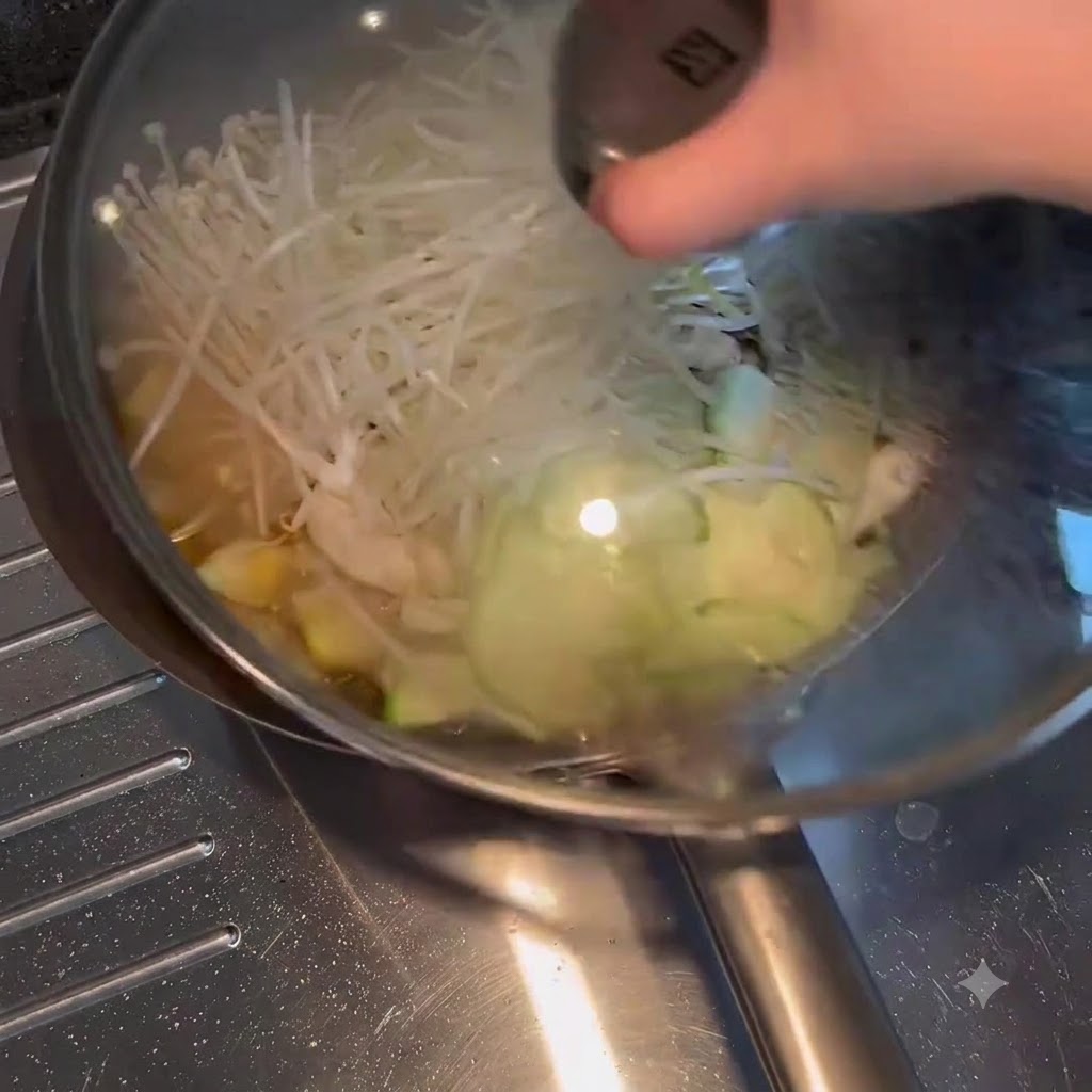 野菜とスープが入ったフライパンにガラスの蓋が置かれている様子。