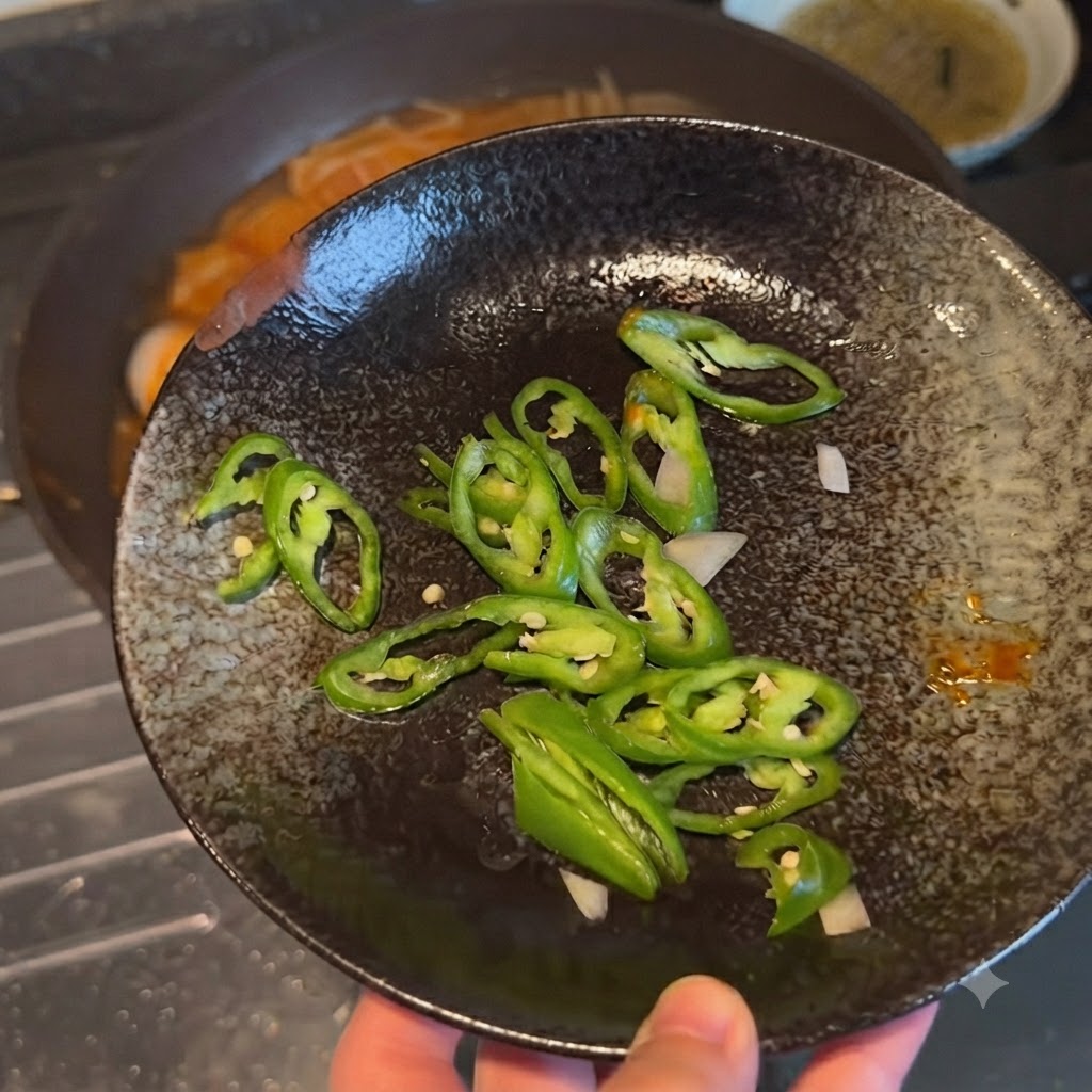 料理に加える前に、濃い色の皿に盛られたスライス青唐辛子の様子。
