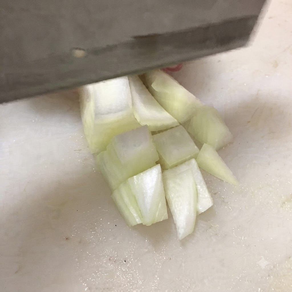 白いまな板の上で包丁を使い、木綿豆腐を厚めのサイコロ状に切っている様子。