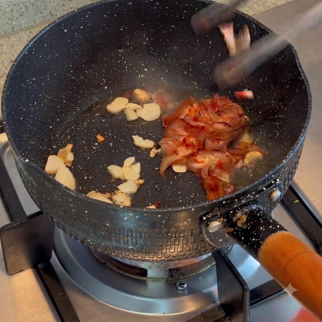 鍋の中で炒めたにんにくと一緒にキムチを炒め合わせている様子