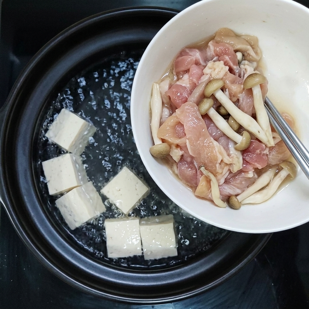 下味をつけた豚肉のスライスとキノコを一緒に沸騰した鍋に加えているところ。
