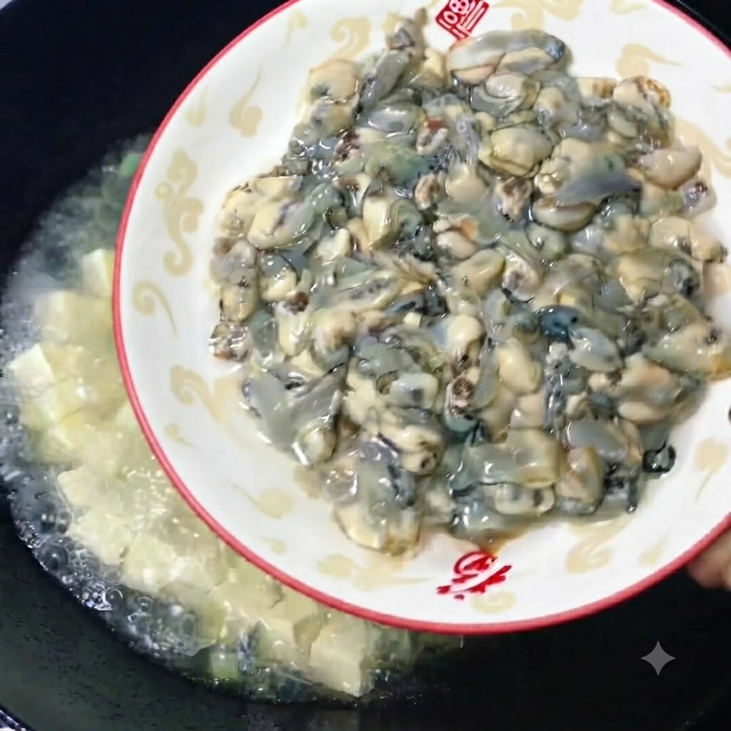 新鮮でぷりっとした生牡蠣を美しい皿から、豆腐のスープが煮立つ中華鍋に滑り込ませている様子