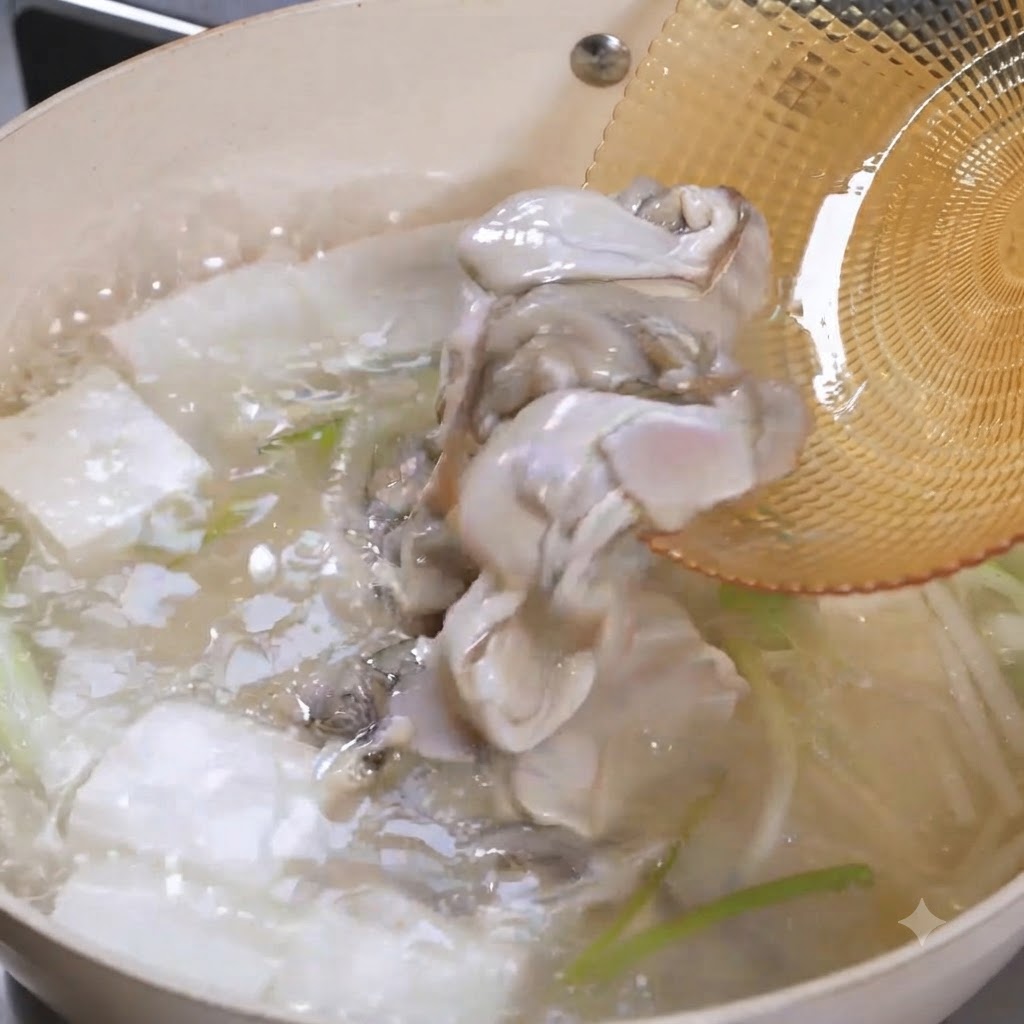 スキマースプーンから、沸騰した豆腐スープの中に生の牡蠣が滑り落ちていく様子。