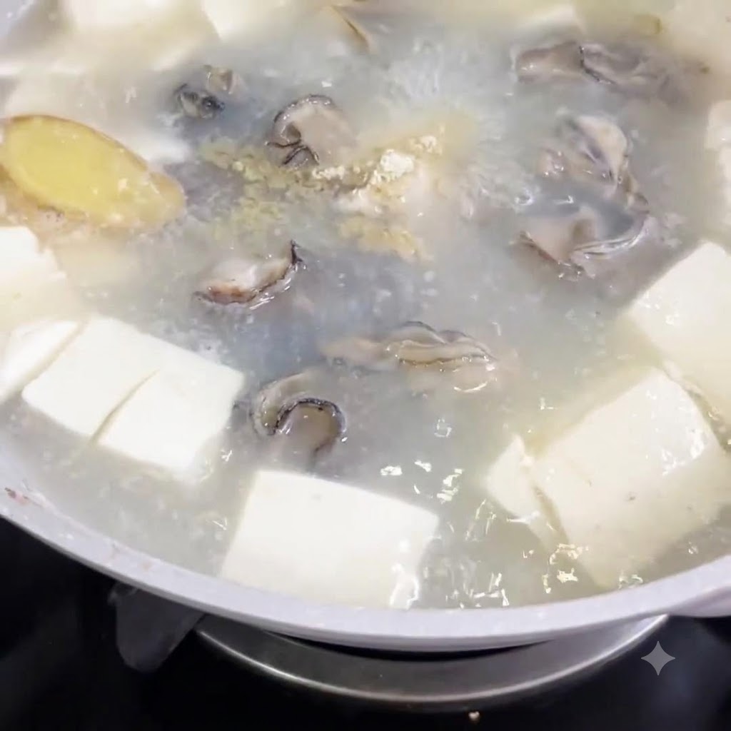 豆腐のキューブと牡蠣が入った沸騰したスープの鍋に白こしょうが振りかけられている様子