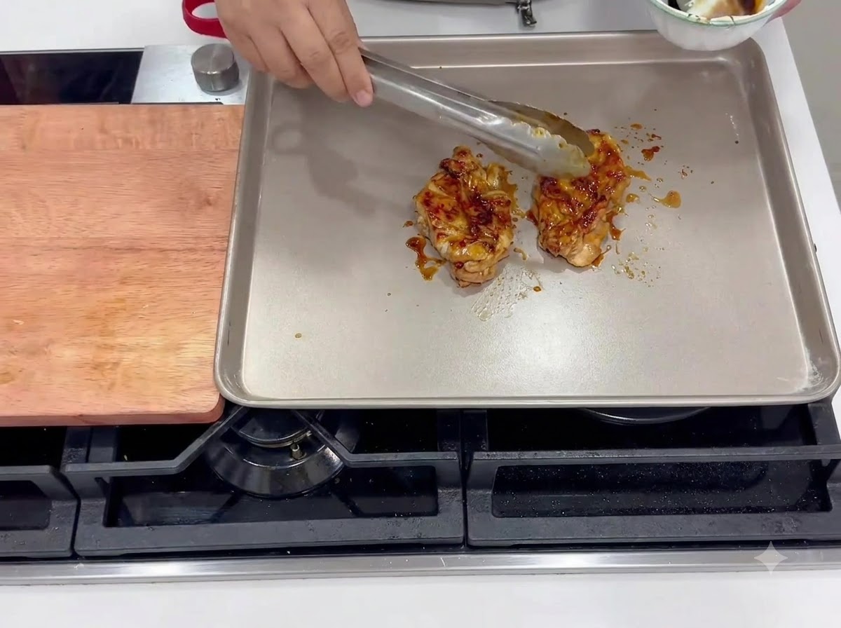 加熱した四角いフライパンで、皮を下にして揚げ焼きにされているマリネ済みの鶏もも肉。