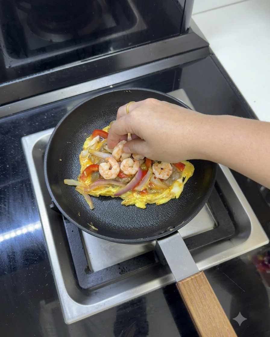 フライパンの中の卵と野菜の混合物の上に、溶けるスライスチーズが置かれている様子。