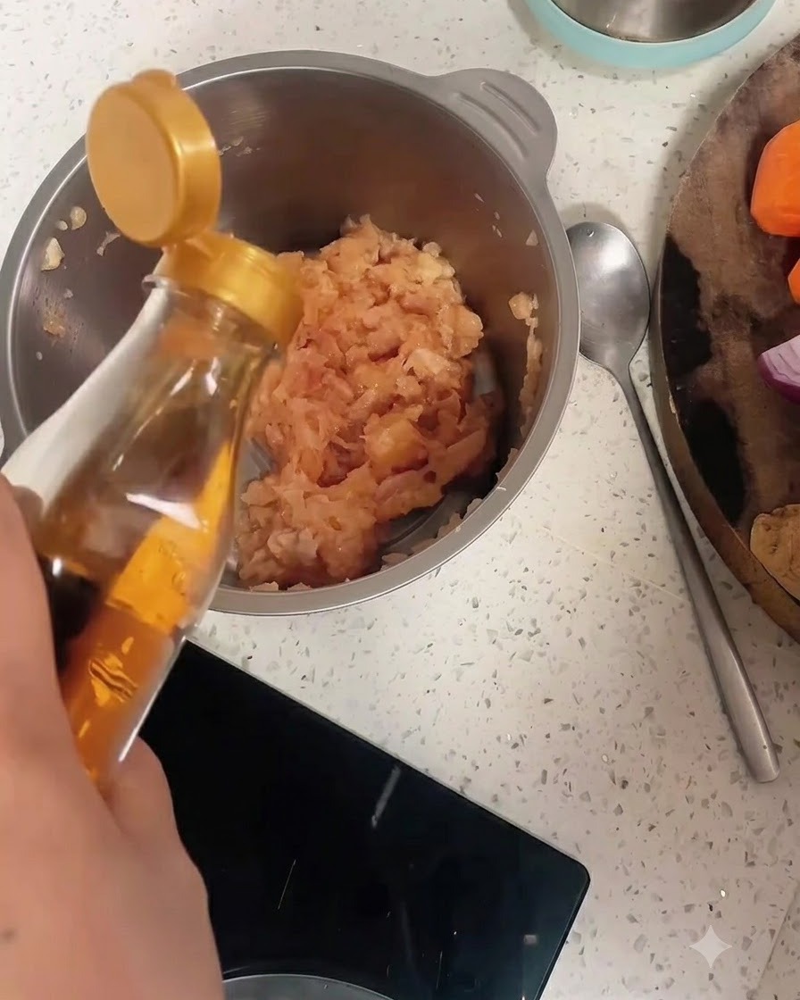 ひき肉とコショウの入ったステンレス製のボウルに、ボトルから料理酒が注がれている様子。