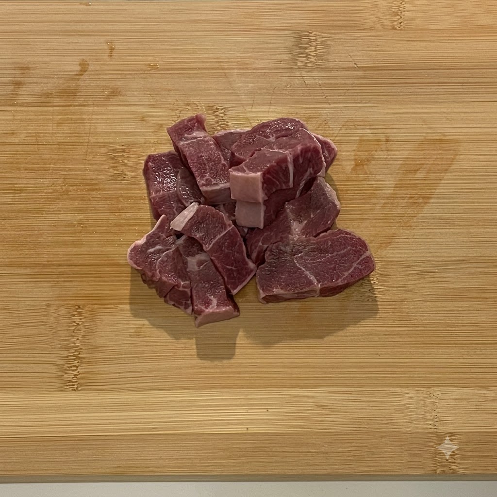 スチール製のフードプロセッサーのボウルに入れられた生牛肉の塊。