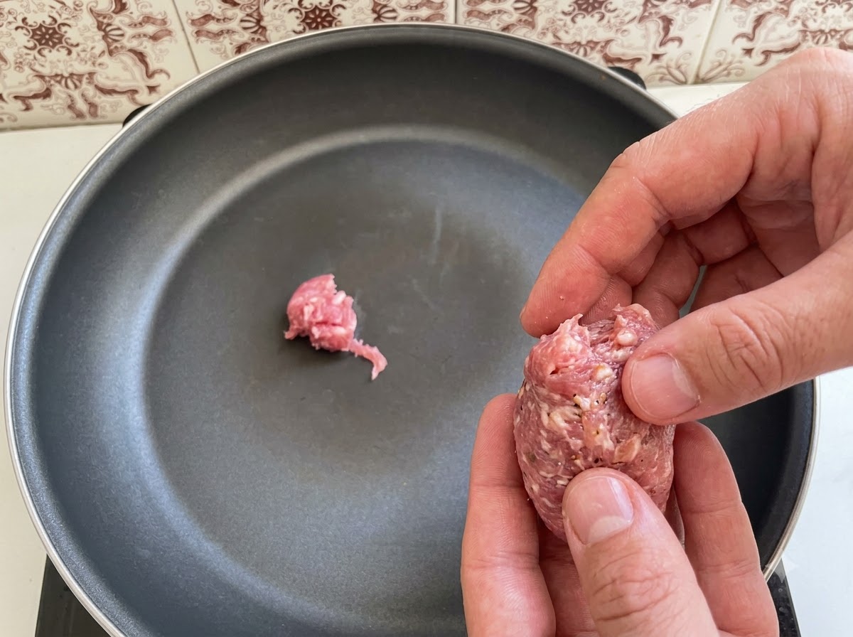 イタリアンソーセージの塊がフライパンに並べられていく様子。