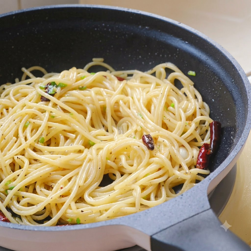 フライパンの中のパスタに、刻んだフレッシュなコリアンダーの葉、海塩、黒こしょうを振りかけている様子。